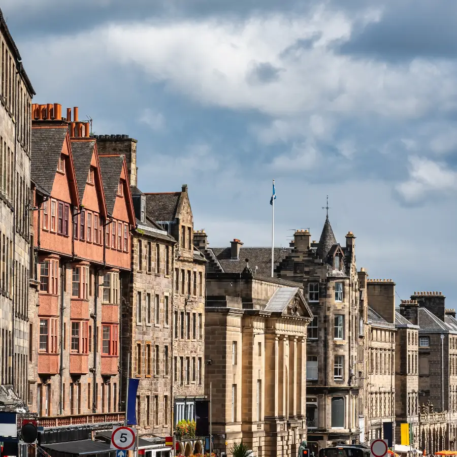 Historic buildings along the Royal Mile in Edinburgh, Scotland, beneath a dramatic cloudy sky.