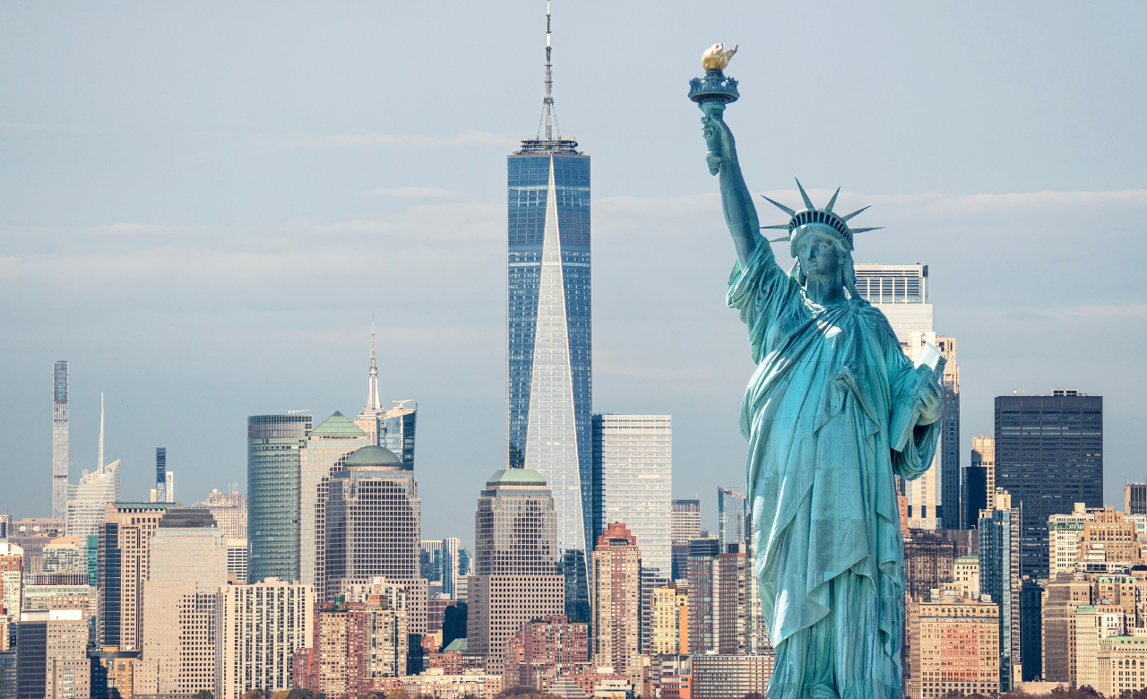 Statue of Liberty overlooking the New York City skyline, with One World Trade Center rising in the background.