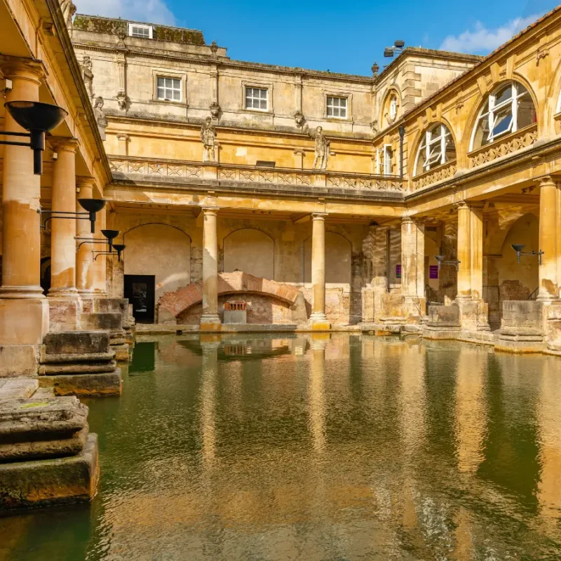 Roman Baths in Bath, England, featuring historic stone architecture, columns and the ancient thermal pool.